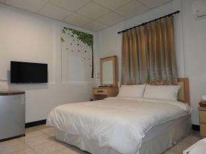 um quarto com uma cama branca e uma televisão em Mediterranean B&B em Fushan