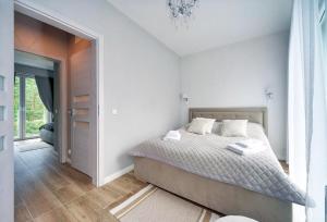 a white bedroom with a bed and a door at Apartamenty Sun Seasons 24 - Four Seasons in Pobierowo