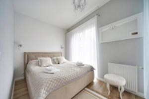 a white bedroom with a bed and a window at Apartamenty Sun Seasons 24 - Four Seasons in Pobierowo