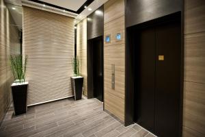 a hallway with a black door and two potted plants at Sotetsu Fresa Inn Chiba Kashiwa in Kashiwa