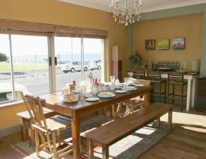 a dining room with a wooden table with chairs and a kitchen at Dolphin Inn Guesthouse in Cape Town