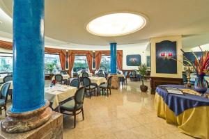 un restaurant avec des tables, des chaises et des colonnes bleues dans l'établissement Hotel Columbus sul Lago, à Bolsena