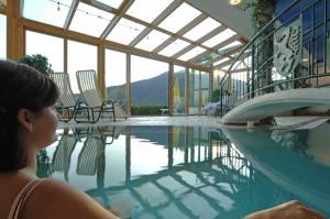 a woman sitting next to a swimming pool at Hotel Jagdhof in Ramsau am Dachstein