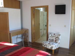 a bedroom with a bed and a chair and a mirror at Quinta dos Castanheiros - Turismo Rural in Negreda
