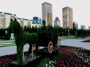 een standbeeld van een paard dat een kar trekt in een park bij Infinity House in the center in Astana