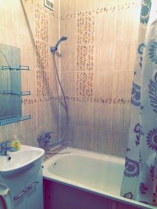 een badkamer met een wastafel, een bad en een douche bij Infinity House in the center in Astana