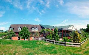 una casa grande con una valla en un campo en Landhaus Ostseeblick en Kronsgaard