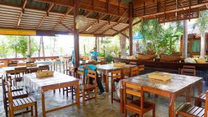 a restaurant with tables and chairs and a person in the background at Baan Siriporn Resort - โรงแรมบ้านศิริพร รีสอร์ท in Samut Songkhram