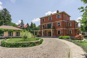 a large red brick house with a driveway at The Belgrade Hills Rooms and Suites in Belgrade