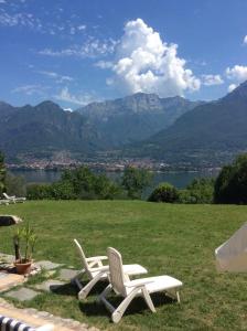 two white chairs in a field with a view of mountains at Villa Oliveto apartments in Oliveto Lario