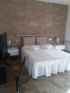 Un dormitorio con una cama blanca con dos mesas y un televisor. en Tonini House, en Casa Cavallini