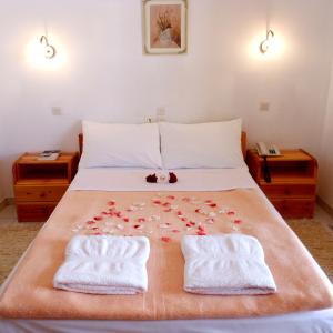 a bed with two towels and flowers on it at Studios Maria in Paralio Astros