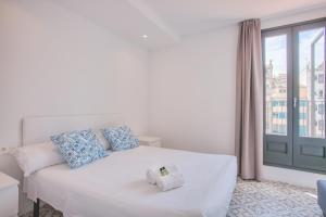 Un dormitorio con una cama blanca con almohadas azules y una ventana en Flateli Rambla 5 2-1, en Girona