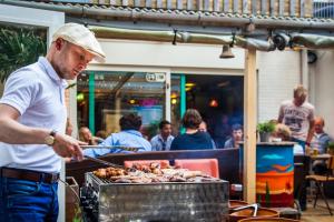 a man is preparing food on a grill at Jorplace Boutique Hostel in Scheveningen