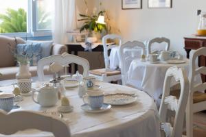 un comedor con mesas blancas y sillas blancas en Akrogiali, en Posidhonía