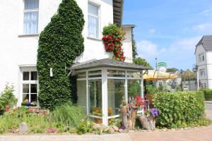 ein weißes Haus mit einem Wintergarten mit Blumen darauf in der Unterkunft Baltisches Haus Pension Moll in Zinnowitz