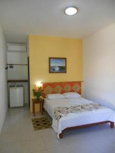 um quarto com uma cama grande e uma parede amarela em Pousada Araçás Village em Imbassaí