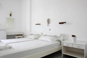 two beds in a bedroom with white walls at Hotel Zannet in Parikia