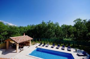a swimming pool with chairs and a gazebo at Vila Foška in Žminj