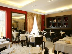 a restaurant with white tables and chairs and a mirror at Albergo Ristorante Marcheno in Marcheno