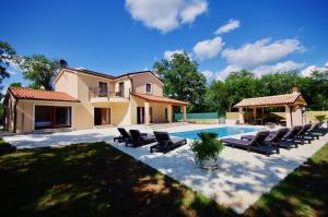 a villa with a swimming pool and lounge chairs at Vila Foška in Žminj