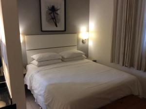 um quarto com uma grande cama branca e 2 almofadas em Ipa Penthouse Prudente no Rio de Janeiro