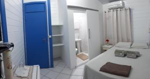 a small bathroom with a bed and a blue door at Oceano Azul Noronha in Fernando de Noronha