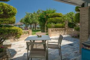 a table and chairs on a patio with trees at Fiore Beach Studios in Vasilikos