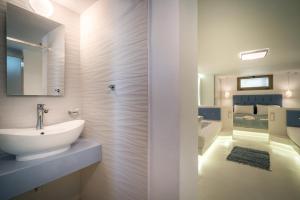 a white bathroom with a sink and a mirror at Fiore Beach Studios in Vasilikos