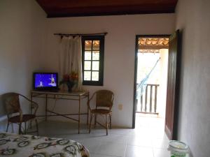 1 dormitorio con 1 cama y 1 mesa con TV en Pousada Araçás Village en Imbassai