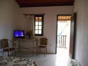 a bedroom with a bed and a table with a television at Pousada Araçás Village in Imbassai