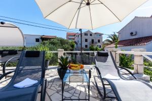 a table with a bowl of fruit and an umbrella on a balcony at Villa Sarah in Supetar