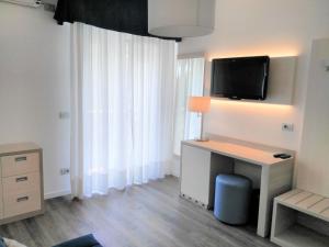 a room with a desk and a tv on a wall at Hotel Abbazia in Lignano Sabbiadoro