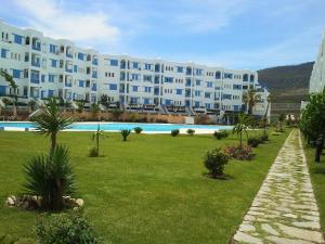 a large apartment building with a lawn and a swimming pool at Jawhara Smir Marina Smir in Marina Smir