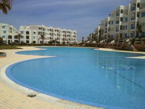 een groot blauw zwembad voor sommige appartementengebouwen bij Jawhara Smir Marina Smir in Marina Smir
