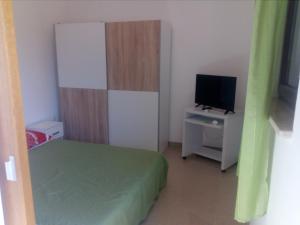 a small room with a bed and a desk with a television at Apartments Vitae in Pula