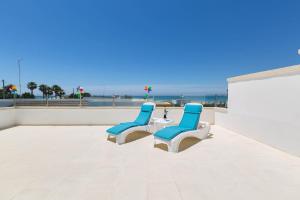 トッレ・ラピッロにあるVilla Belvedere by BarbarHouseのビーチのあるパティオ(青と白の椅子3脚付)