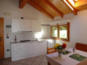 una cucina con armadi bianchi e un tavolo con fiori di Casa Solaris a Fai della Paganella