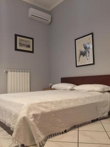 エルコラーノにあるB&B Eracleの白いベッド1台、壁に2枚の写真が飾られたベッドルーム1室