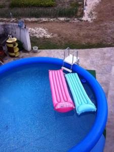 Una piscina azul con tres zapatillas de colores. en A quinta do Avo Jorge, en Martingança