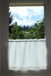 - une fenêtre avec un rideau blanc dans la chambre dans l'établissement La casa dei nonni, à Tassullo