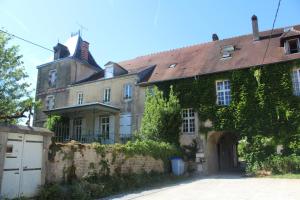 una vieja casa con hiedra a un lado. en Gîte du château de Feschaux, Jura en Villeneuve-sous-Pymont