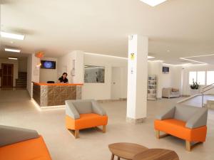 a lobby with orange chairs and a person in the background at Apartamentos Mar i Vent in San Antonio