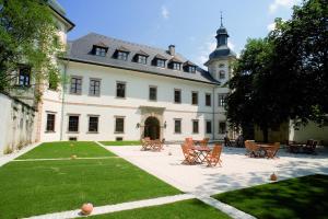 un gran edificio blanco con sillas y un patio en JUFA Hotel Schloss Röthelstein, en Admont