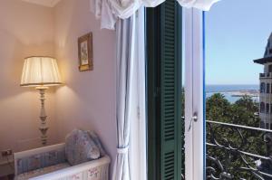 a bedroom with a window overlooking the ocean at Hotel De Paris Sanremo in Sanremo