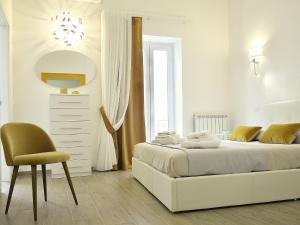 una camera da letto bianca con un letto e una sedia di Duca70 "Suite Home" a Taranto