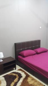 - une chambre avec un lit avec des draps violets et une table dans l'établissement Taman Tanjung Minyak, à Malacca