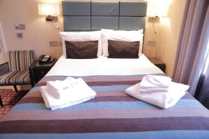a bed with a white comforter and pillows at Astors Belgravia in London