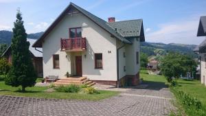 Dieses weiße Haus verfügt über eine Veranda und einen Balkon. in der Unterkunft Pokoje Gościnne A.T. Mikołajczyk in Krościenko nad Dunajcem