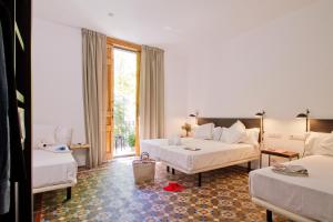 バルセロナにあるソム ニット トゥリオンフのベッド2台とソファが備わるホテルルームです。